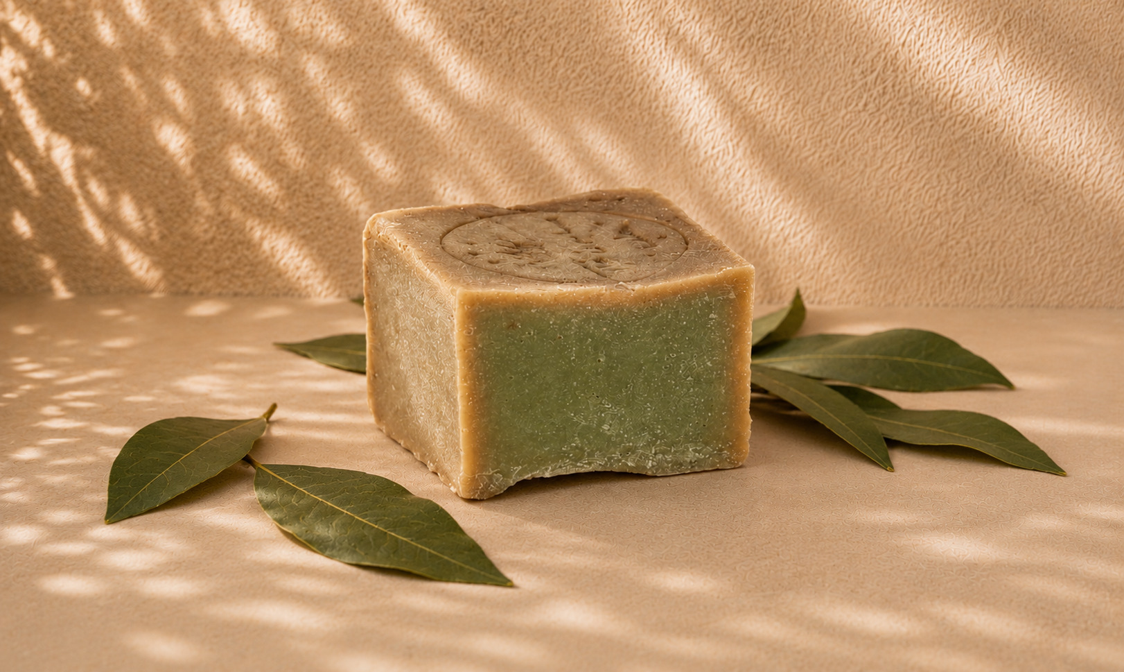 Stacked bars of green Aleppo soap in a calm Mediterranean bathroom setting, soft daylight